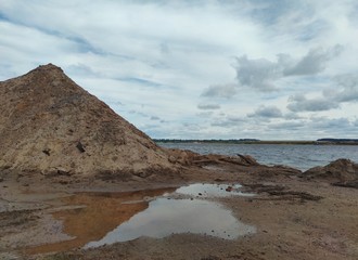 sandy mountain near coastline against blue cloudy sky