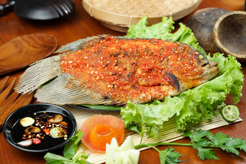 Fried fish sprinkled with hot chili sauce on a wooden table. Usually used for menu list pictures or food pictures in restaurants. Top view