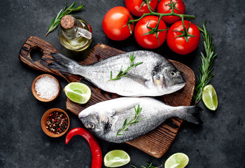 Raw dorado fish with ingredients on stone background