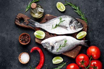 Raw dorado fish with ingredients on stone background