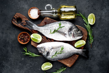 Raw dorado fish with ingredients on stone background