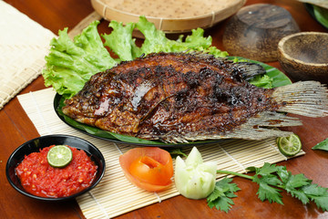 photos of food products, View from above Close up of grilled fish or grilled gouramy with chili sauce and vegetables on a textured wooden table. Usually used for menu list pictures or food pictures in