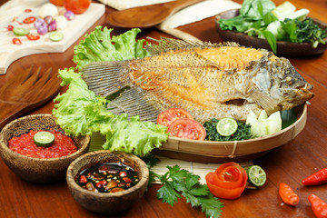 photos of food products, Close up of fried fish or fried gouramy with chili sauce and vegetables on a textured wooden table. Usually used for menu list pictures or food pictures in restaurant. top vie
