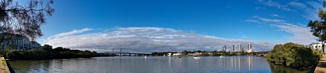 Fototapeta na wymiar Beautiful panoramic view of high-rise buildings on the riverbank on a sunny day with deep blue sky and light clouds, Parramatta river, Meadowbank, Sydney, New South Wales, Australia 