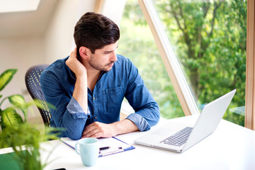 Stressed businessman using laptop while working from home