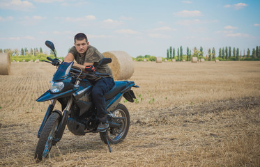 Obraz na płótnie Canvas Young man on a motorcycle at field, hobby of modern people, lifestyle 