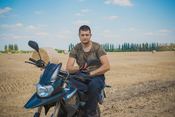 Young man on a motorcycle at field, hobby of modern people, lifestyle 