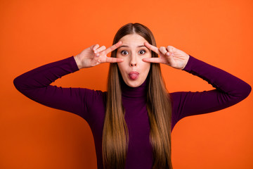 Photo of careless dreamy girl have free time fooling make v-sign face eye show tongue out wear jumper isolated over bright shine color background