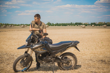 Naklejka na ściany i meble Young man on a motorcycle at field, hobby of modern people, lifestyle 