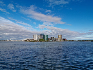 Beautiful view of high-rise buildings on the riverbank on a sunny day with deep blue sky and light clouds, Parramatta river, Meadowbank, Sydney, New South Wales, Australia
