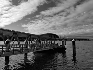 Fototapeta premium Beautiful black and white view of a wharf along a river on a sunny day with clouds, Parramatta river, Meadowbank, Sydney, New South Wales, Australia 