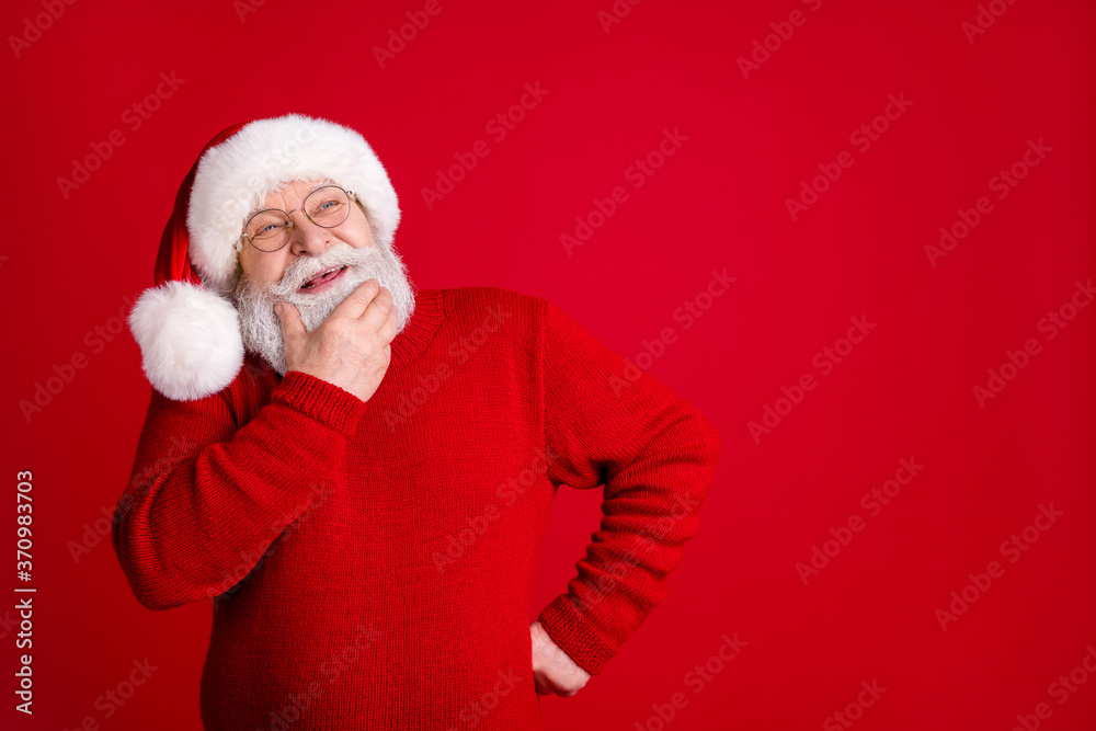 Wall mural Photo of dreamy thoughtful old man in santa claus headwear look copyspace touch chin face think magic fairy x-mas gifts wear stylish trendy sweater isolated bright shine color background