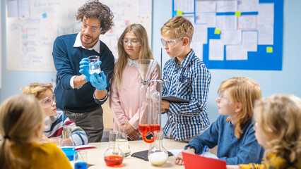 Elementary School Science Classroom: Enthusiastic Teacher Explains Chemistry to Diverse Group of Children, Shows them How to Mix Chemicals in Beakers. Children Look with Interest and Talk