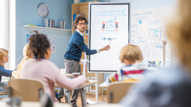 Elementary School Physics Teacher Uses Interactive Digital Whiteboard to Show to a Classroom full of Smart Diverse Children how Renewable Energy Works. Science Class with Kids Listening - Powered by Adobe