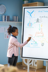 Elementary School Science Class: Cute Girl Uses Interactive Digital Whiteboard to Show to a...