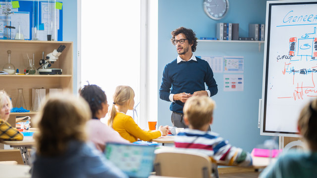 Elementary School Physics Teacher Uses Interactive Digital Whiteboard to Show to a Classroom full of Smart Diverse Children how Renewable Energy Works. Science Class with Kids Listening