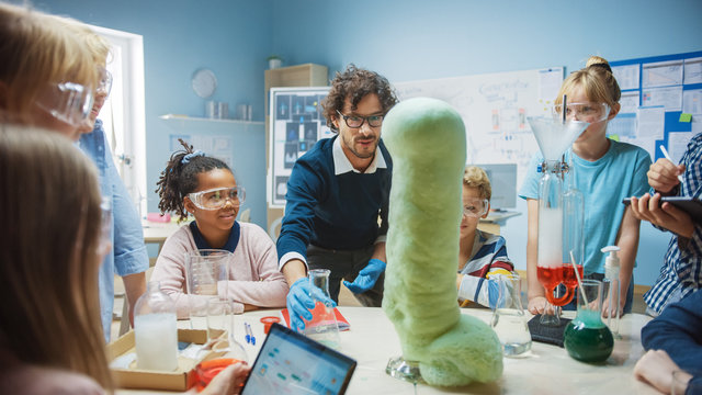 Elementary School Science / Chemistry Classroom: Enthusiastic Teacher Shows Funny Chemical Reaction Experiment to Group of Children. Mixing Chemicals in Beaker so they Shoot Foam (Elephant Toothpaste)