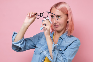 Caucasian woman cleaning glasses or lens with microfiber tissue