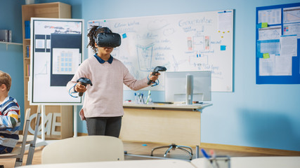 Elementary School Computer Science Class: Cute Girl Wearing Augmented Reality Headset and Using Controllers Learns Lessons in Virtual Reality Excited, Curious and Interested in Knowledge