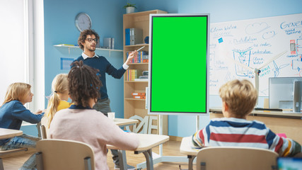 Elementary School Teacher Uses Interactive Digital Whiteboard With Green Screen Mock-up Template. He Leads Lesson to Classroom full of Smart Diverse Children. Science Class with Kids Listening