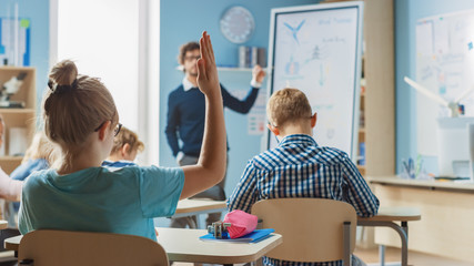 Brilliant Schoolgirl Raises Hand with an Answer. In Elementary School with Group of Bright Multiethnic Kids Learning Science. Back View Shot