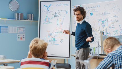 Elementary School Physics Teacher Uses Interactive Digital Whiteboard to Show to a Classroom full of Smart Diverse Children how Renewable Energy Works. Science Class with Kids Listening