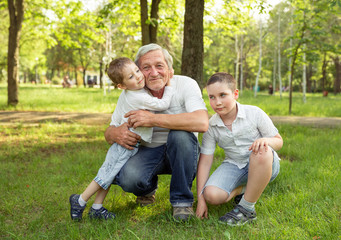 Naklejka na ściany i meble Senior man and grandsons are hugging and smiling, resting together