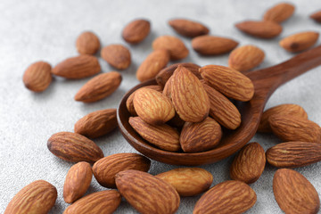  Almonds in wooden spoon on gray background,Close up,Copy space.