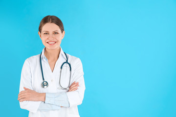 Fototapeta premium Portrait of young doctor with stethoscope on blue background, space for text