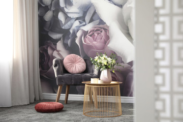 Fototapeta na wymiar Comfortable armchair near wall with floral print. Stylish room interior