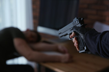 Man with gun and his victim in room, closeup. Dangerous criminal