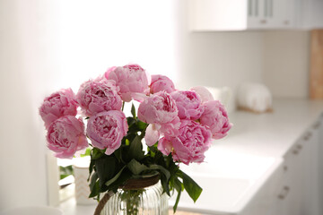 Vase with bouquet of beautiful pink peonies in kitchen