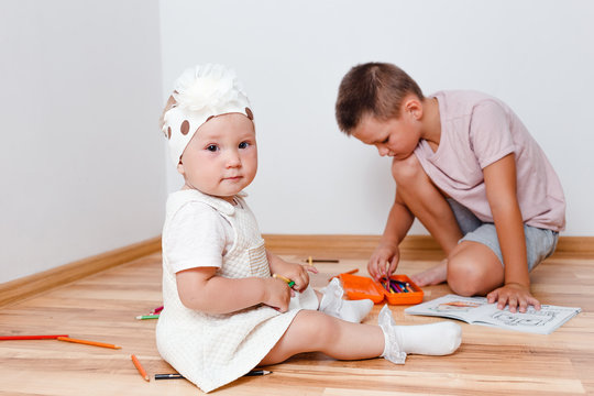 Children At Home. Baby Girl And Older Brother With Colored Pencils