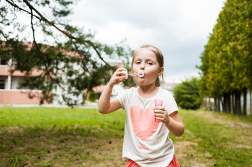 Cheerful girl inflates soap bubbles