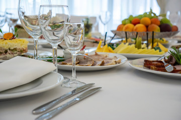 beautiful table setting in light colors with dishes and assorted food on a table with a white tablecloth for a party, wedding or other special event. Restaurant business and service industry concept.