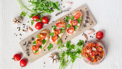 Italian bruschetta with tomatoes and greens on wooden cuting board, overview