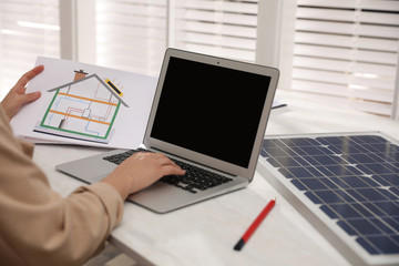 Woman working on house project with solar panels at table in office, closeup