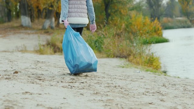 Child carries a heavy bag with garbage. Park cleaning and environmental care