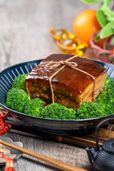 Dong Po Rou (Dongpo pork meat) in a beautiful blue plate with green broccoli vegetable, traditional festive food for Chinese new year cuisine meal, close up.