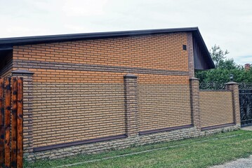 long brown fence of brick  in green grass on the street