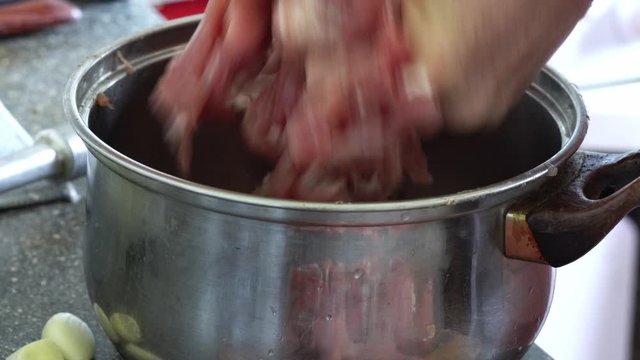 woman crush raw meat in a saucepan. Cooking and preparing meat on wooden cutting board.