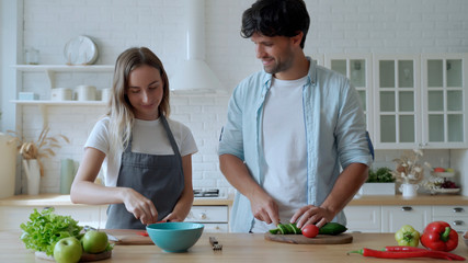Young happy couple is enjoying and preparing healthy meal in their kitchen