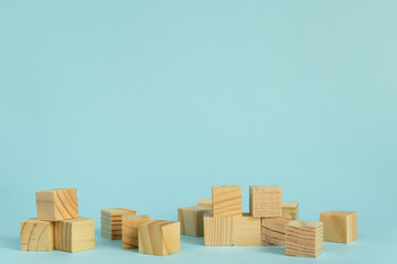 Construction of wooden cubes on blue background with copy space. Mockup composition for design