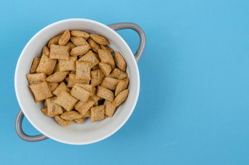 Bowl with sweet corn pads with chocolate inside on a blue background, copy space, top view