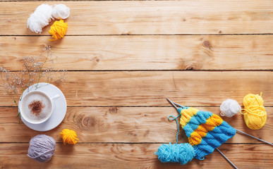 Yarn in warm colors on a white wooden board. Yellow, blue, beige, white and green. The beginning of the process of knitting a women's sweater. Female hobbies, knitting.