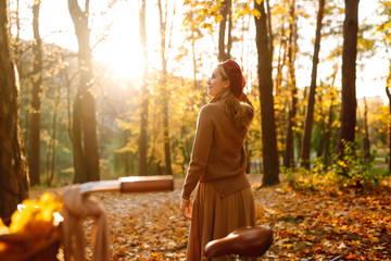 Stylish woman  with a bicycle enjoying autumn weather in the park. Beautiful Woman walking  in the autumn forest at sunset.