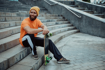 Handsome young stylish hipster guy with beard with a skateboard © San4ezz007