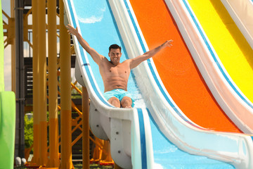 Man on slide at water park. Summer vacation