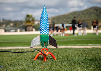Water bottle rocket for school science project prepared for launch with blurred students in the background - Powered by Adobe