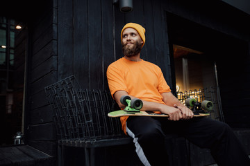 Handsome young stylish hipster guy with beard with a skateboard